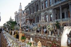 a long table set up for an event with chandelier in the back ground