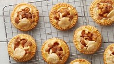 twelve small pies on a cooling rack with some toppings in the top right corner