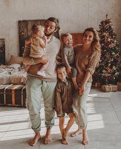 a man, woman and two children standing in front of a christmas tree