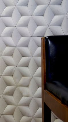 a wooden chair sitting in front of a wall with white tiles on it's sides