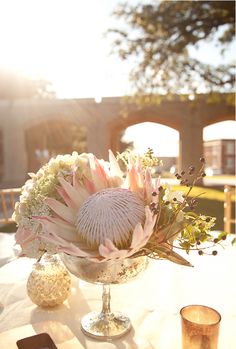 an arrangement of flowers in a glass vase on a table with other items around it