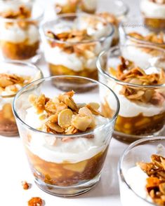 several desserts are arranged in small glass dishes on a table with nuts and whipped cream