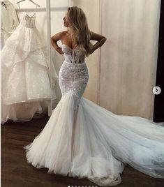 a woman standing in front of a wedding dress and looking at the back of her gown