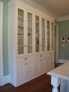 an empty kitchen with white cabinets and wood floors