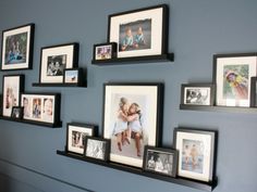 a wall with many pictures on it and some framed photos hanging up against the wall