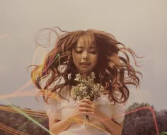 a woman with long hair holding flowers in her hands