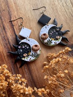 two black and white earrings with pumpkins on them sitting on top of a wooden table