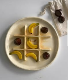 a white plate topped with banana slices and figs next to a bag of olives