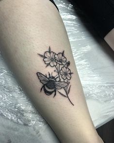 a black and white photo of a flower with a bee on it's arm