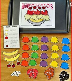 an assortment of cut outs and stickers on a wooden table with a cookie sheet