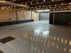 an empty warehouse with lights on the ceiling and concrete flooring in front of it