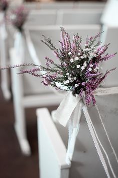 purple and white flowers tied to pews at a wedding