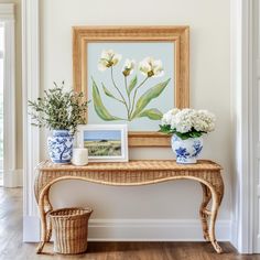 there is a painting on the wall and vases with flowers in them sitting on a table