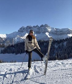 a woman standing on top of a snow covered slope with skis and poles in her hands