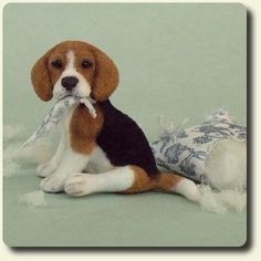 a small beagle puppy chewing on a bone toy in front of a green background