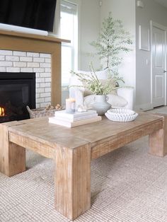 a living room with a fireplace, coffee table and television on top of the tv stand