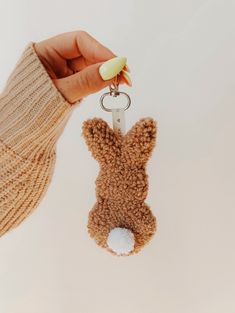 a person holding a keychain with a stuffed animal on it's side