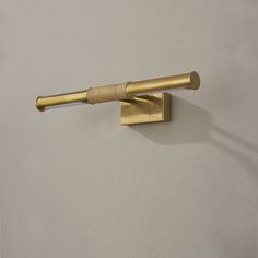 a wall mounted brass toilet paper dispenser on a white wall in a bathroom