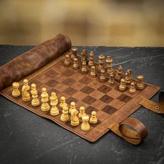 a chess board with pieces on it and a leather case sitting next to the game