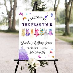 a welcome sign for the eras tour with flowers in front of it on a easel