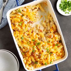 a casserole dish filled with chicken and pasta, garnished with green onions