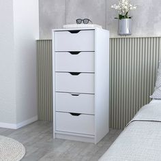 a white chest of drawers in a bedroom next to a bed with eyeglasses on it