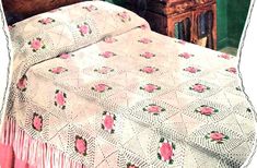 an old fashioned crocheted bedspread with pink roses on it and a wooden dresser in the background