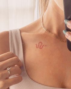 a woman holding a cell phone and looking at her tattoo on her upper back shoulder