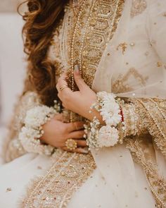 a woman in a white and gold outfit holding flowers