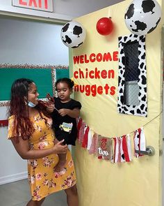 a woman and child standing in front of a sign that says welcome chicken nuggets