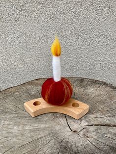 an apple with a candle sticking out of it sitting on top of a piece of wood