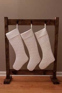 three white christmas stockings hanging from a wooden rack