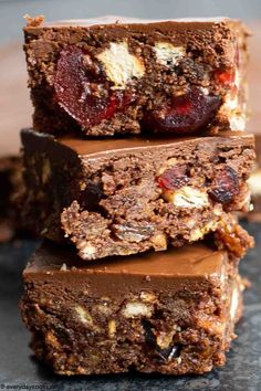 three pieces of chocolate and nuts brownies stacked on top of each other with one bite taken out