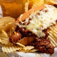 a chili cheeseburger with chips and a drink