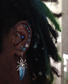 a close up of a person with dreadlocks wearing ear rings and piercings