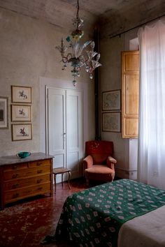 a bedroom with a bed, chair and chandelier hanging from it's ceiling