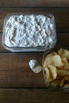 two bowls filled with chips and dip on top of a wooden table