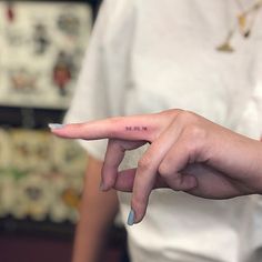 a woman's hand with the word love tattooed on it, pointing to her left side