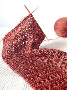 a red piece of yarn sitting on top of a table next to a ball of thread