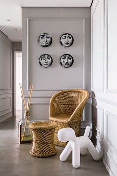 a wicker chair sits in front of three black and white plates on the wall