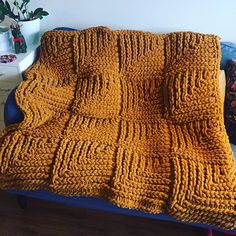 a crocheted blanket sitting on top of a blue couch