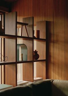 a living room with wood paneling and shelves filled with vases on top of them