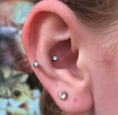 a woman's ear with three piercings on it