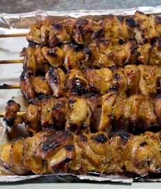 several skewers of chicken sitting on top of tin foil