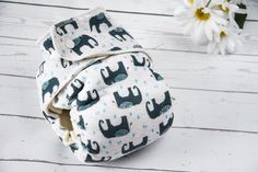 an elephant print cloth diaper cover on a white wooden surface with flowers in the background