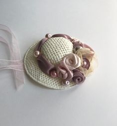 a white hat with pink flowers and pearls on the brim is sitting next to a ribbon