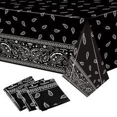 a black table cloth with paisley designs on it and four napkins next to it