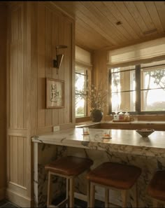 an image of a kitchen setting with marble counter tops and stools in the center