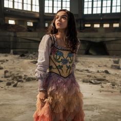 a woman standing in an abandoned building with her hand on her hip and looking up