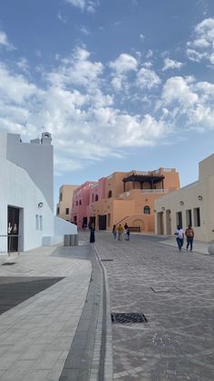 people are walking around in the middle of an open courtyard with buildings on either side